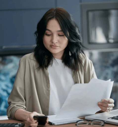 A woman reviewing documents, possibly verifying the details of her credit card debt.