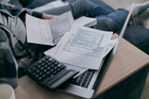 Financial documents and a calculator on a laptop, indicating debt consolidation review.