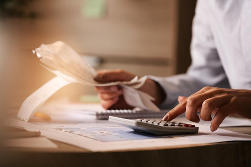 Person using a calculator and reviewing bills, representing the process of managing debt and finances.