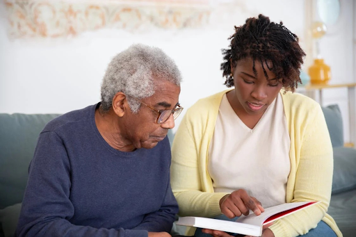 An older man and a younger woman reading a book together, possibly discussing debt management and cease and desist letters.