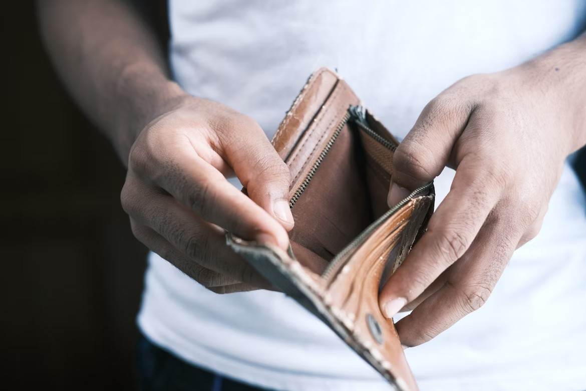 Person holding an empty wallet, symbolizing financial struggle.