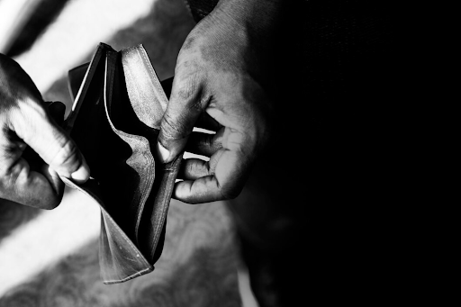 Hands holding an empty wallet, symbolizing financial hardship and debt.