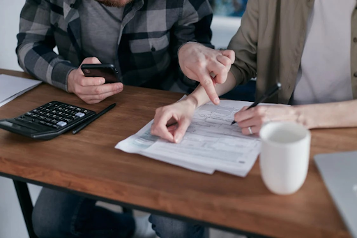 Two people discussing financial documents with a calculator on the table, emphasizing the need for professional advice