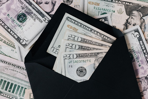 Various U.S. dollar bills inside a black envelope, symbolizing financial planning and debt relief.