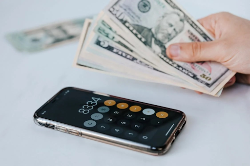 hand holding money and a calculator