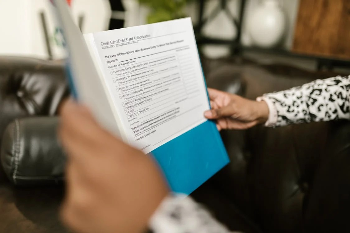 Hands holding a form labeled "Credit Card/Debit Card Authorization," indicating the paperwork involved in debt settlement.