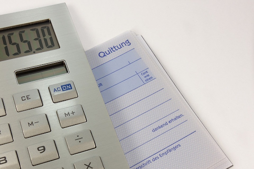 Close-up of a calculator displaying a total amount and a receipt book, representing the process of calculating and tracking personal loan payments.