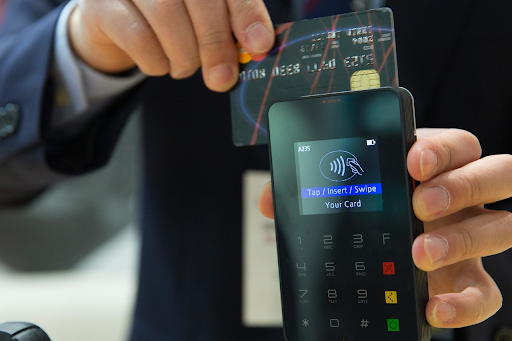 A person inserting a credit card into a payment terminal, illustrating the importance of using credit cards responsibly for managing personal debt.