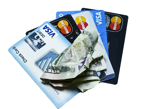 A stack of credit cards and crumpled dollar bills, highlighting the financial burden of multiple credit card debts.