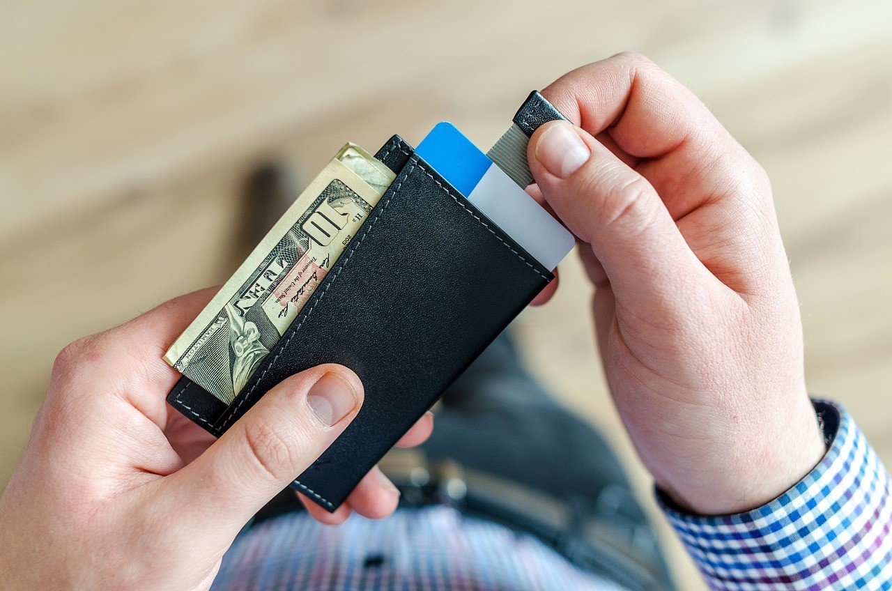 Person holding a wallet with cash and credit cards.