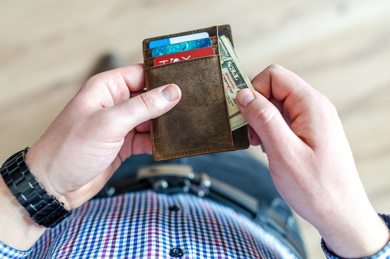A person holding a wallet with credit cards and cash, symbolizing the importance of managing credit card expenses and budgeting for debt relief.