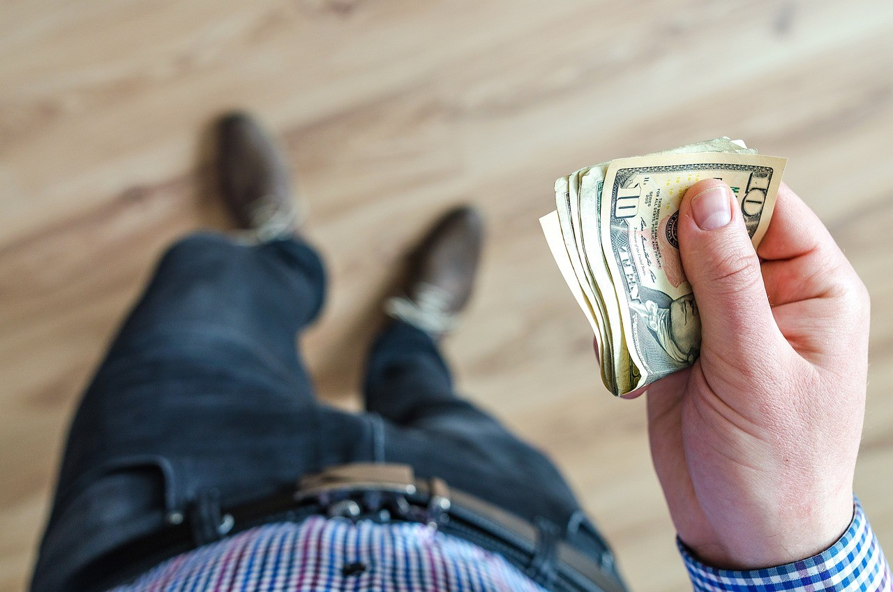 A person holding a stack of cash, representing the potential benefits of debt consolidation.