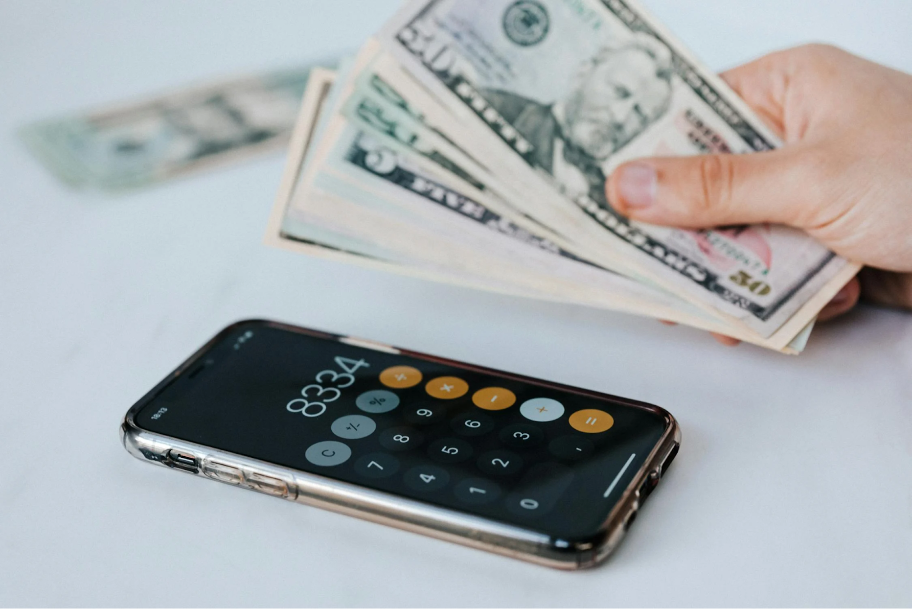 A calculator app on a smartphone and cash