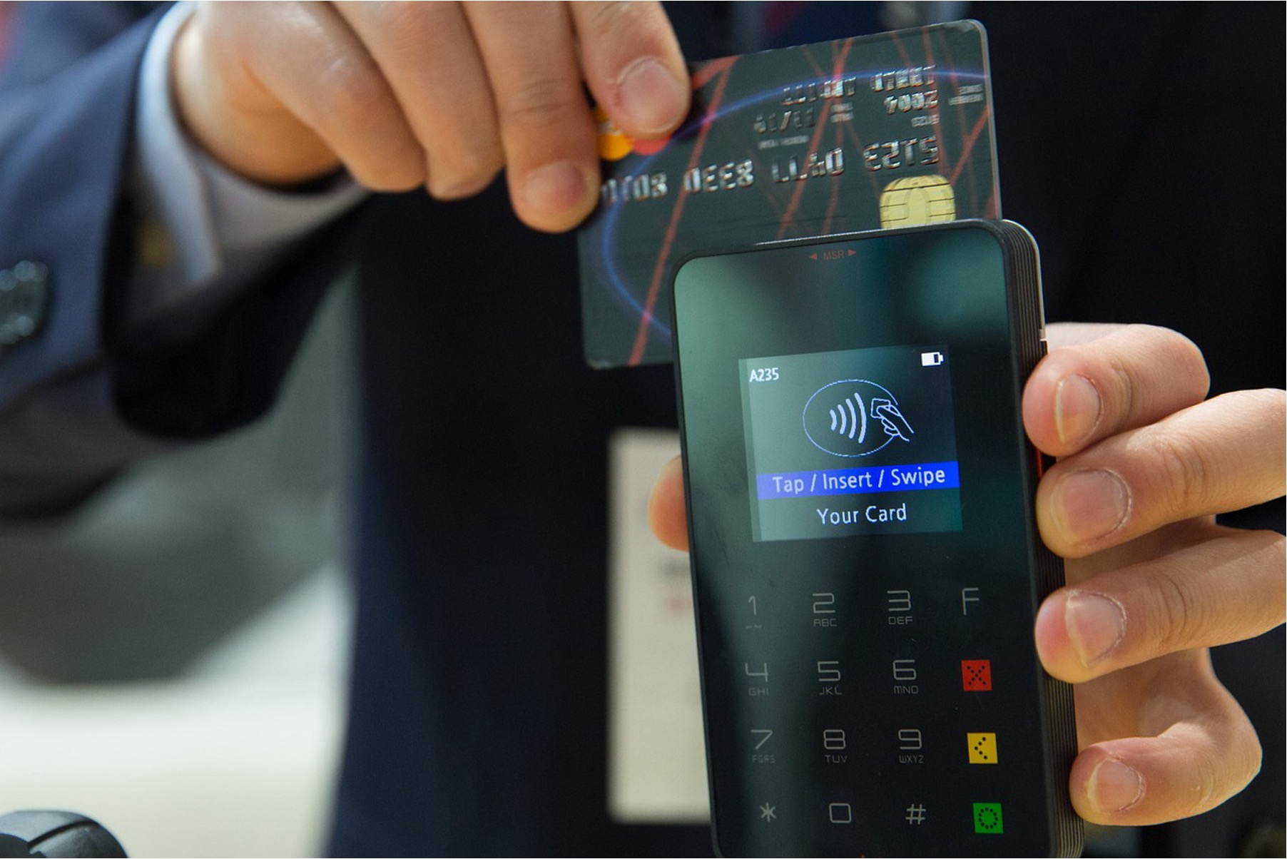 A credit card being swiped on a payment machine.