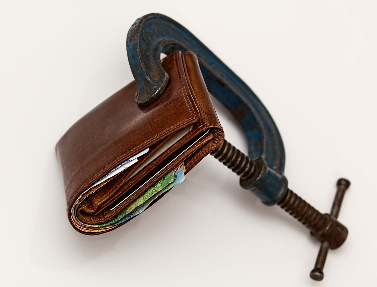 A wallet clamped in a vice, symbolizing financial pressure