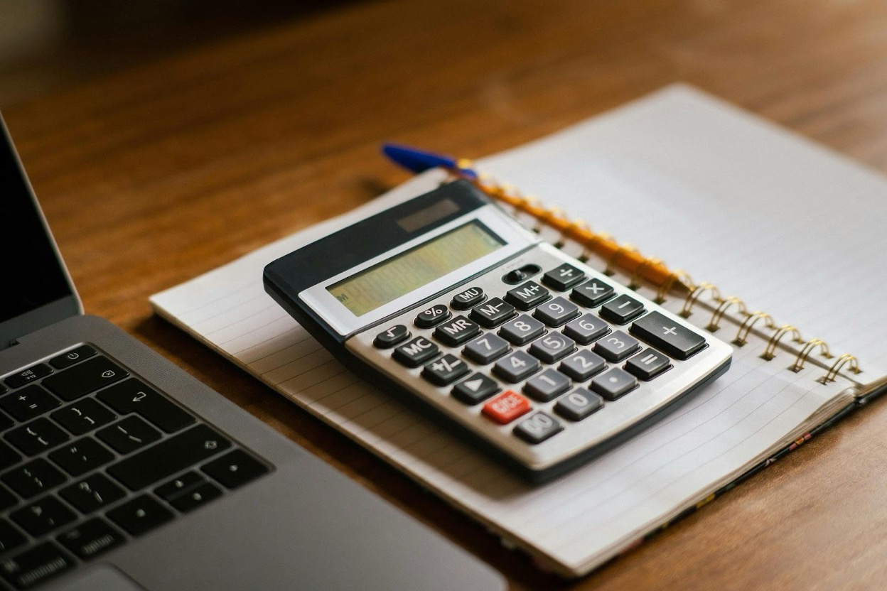 Calculator on a notebook beside a laptop, symbolizing personal financial planning.